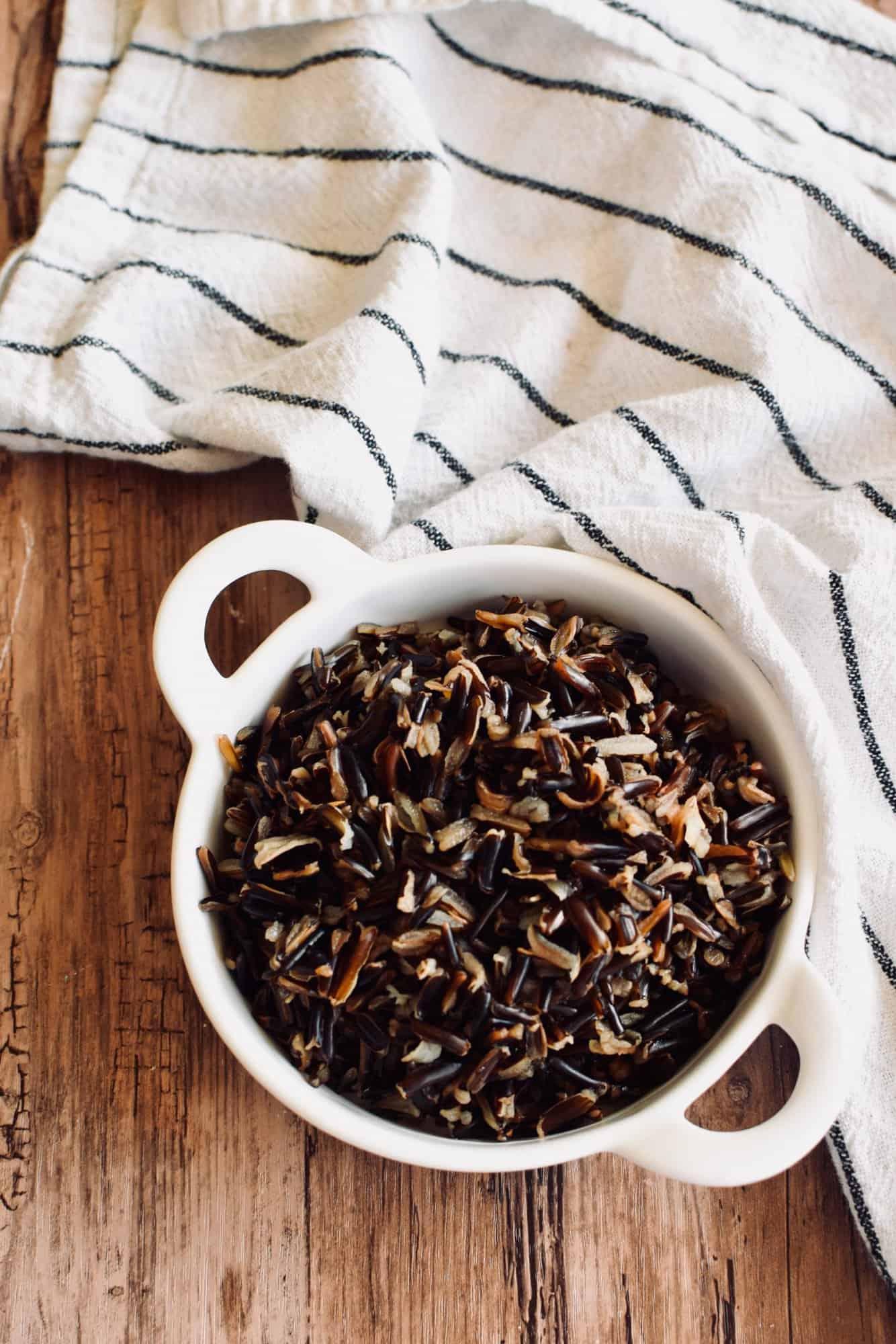 a small bowl of cooked wild rice on a wooden table.