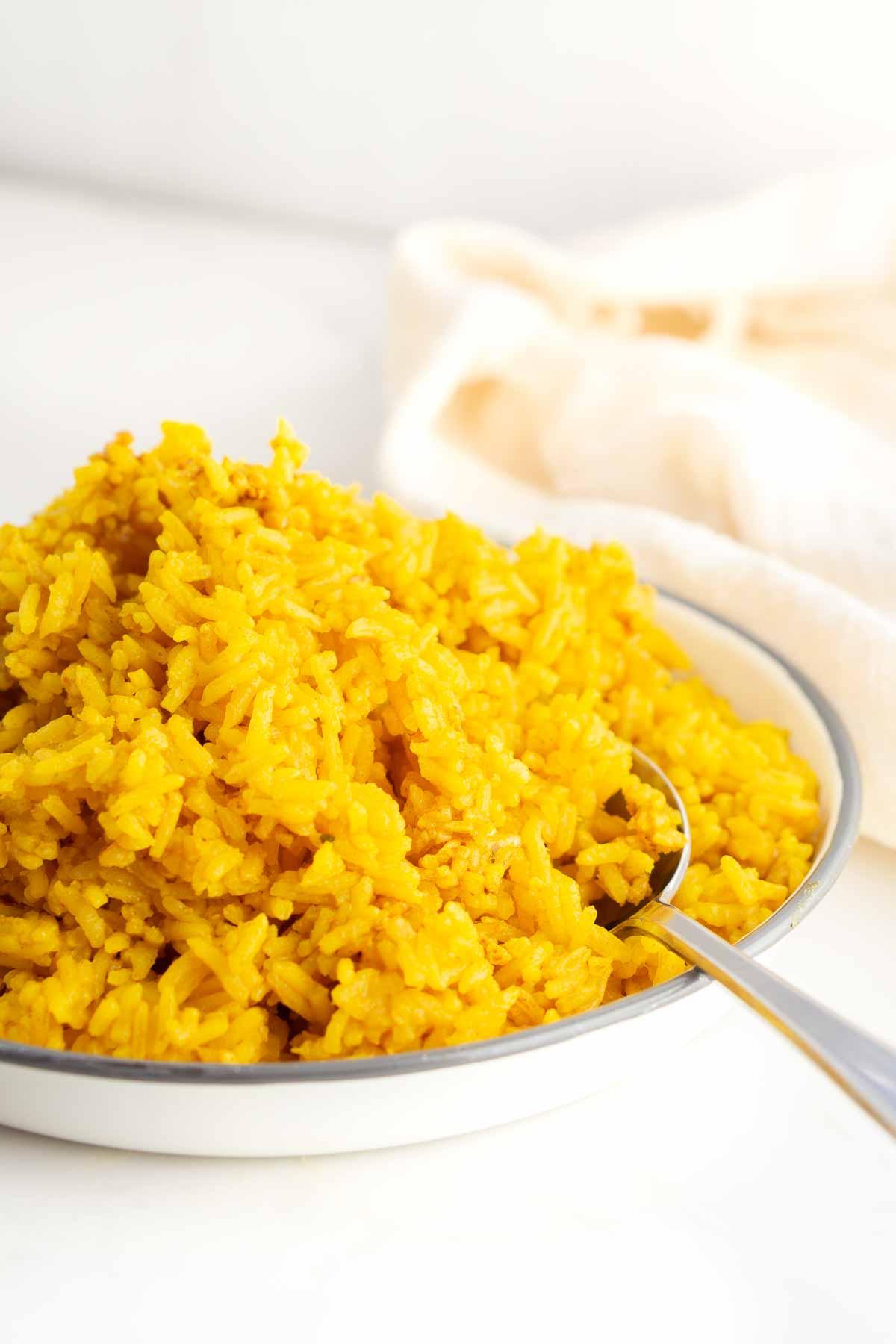 Plate of turmeric rice with spoon for serving