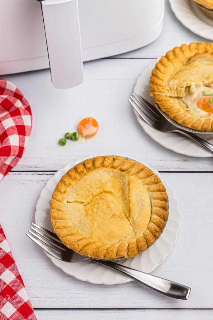 Golden pot pie on a white plate in front of an air fryer.