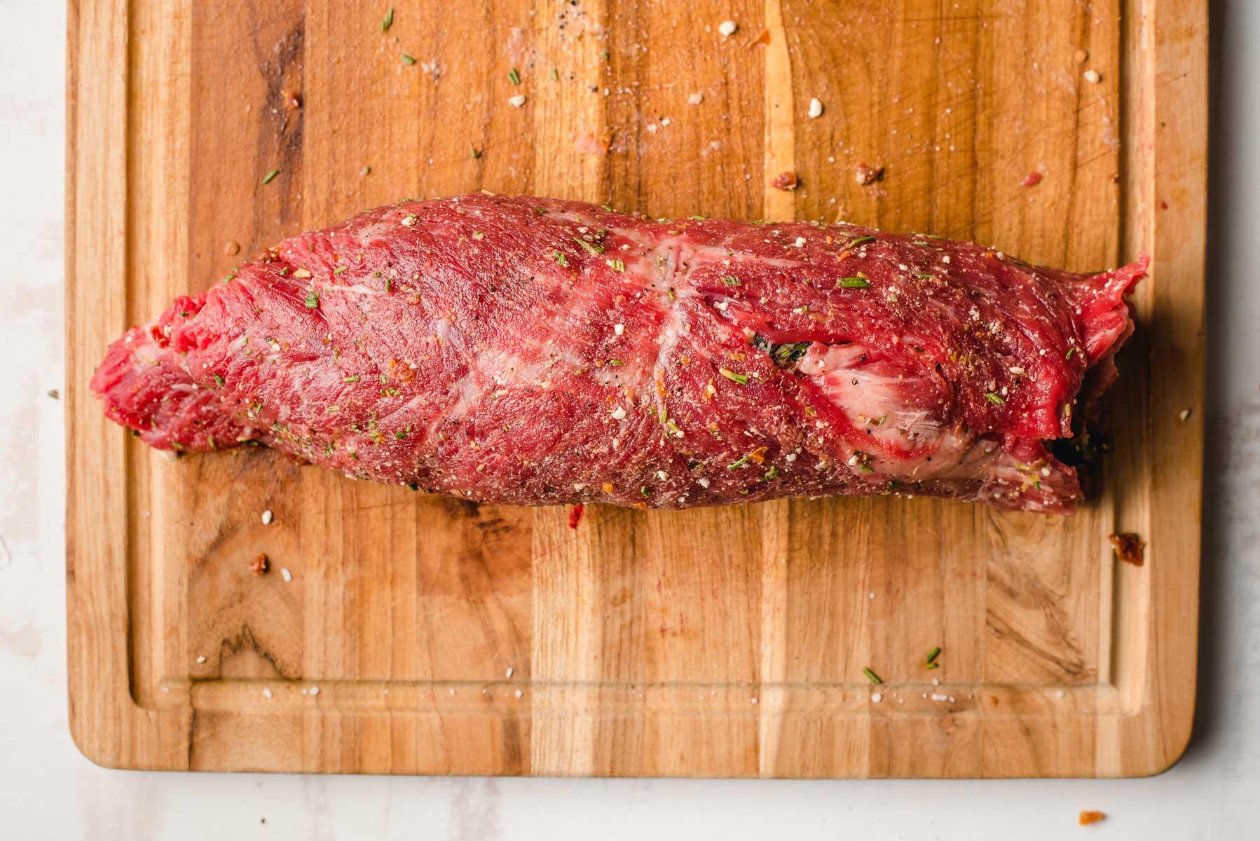Rolled flank steak on a cutting board.