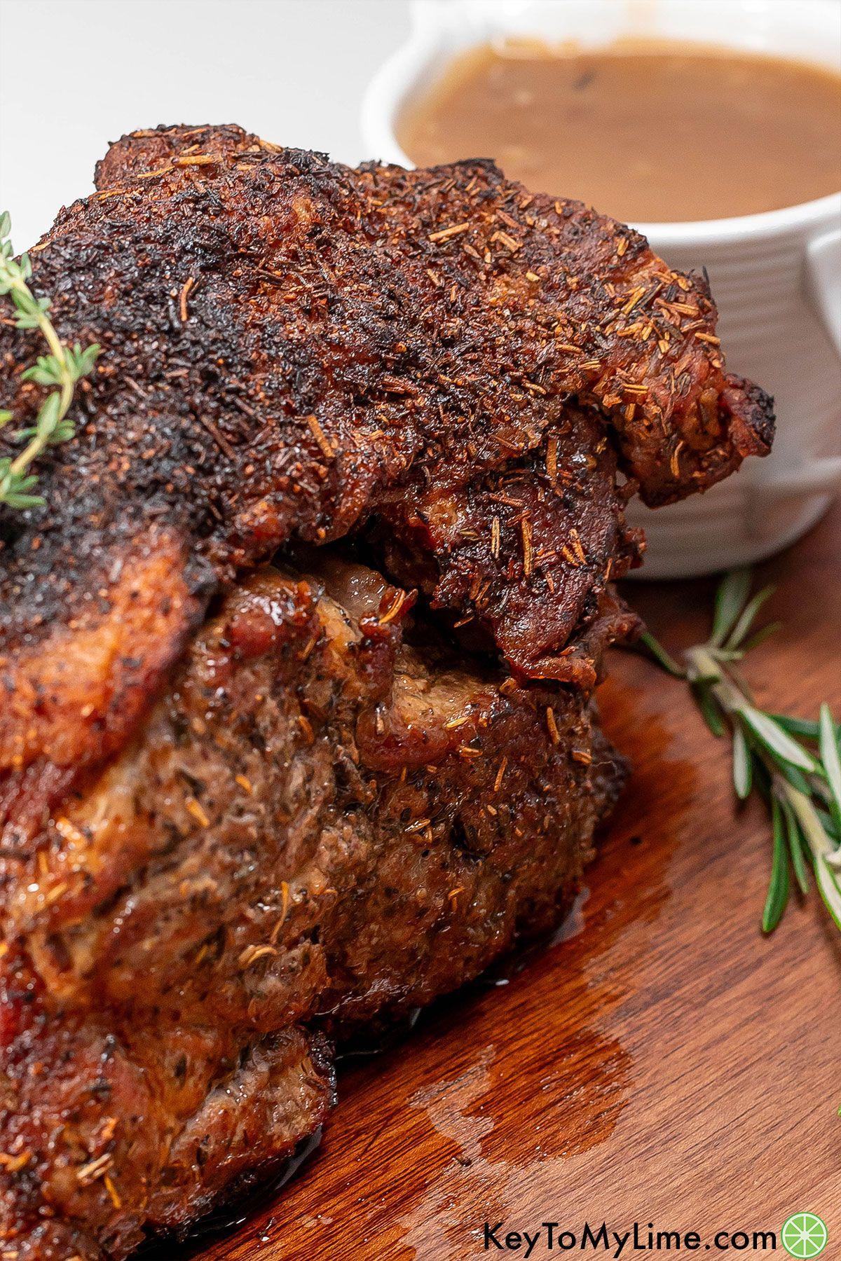 A fully cooked pork roast on a cutting board garnished with thyme.