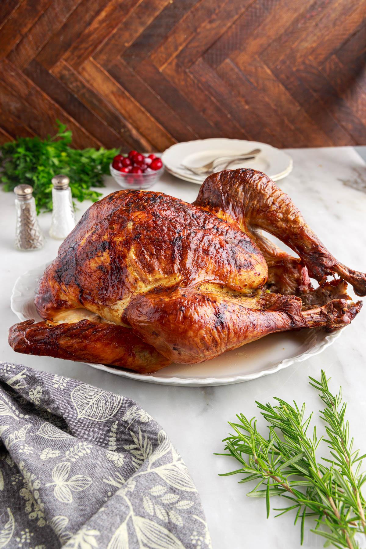 convection oven roasted turkey on a serving platter on a table with fresh herbs