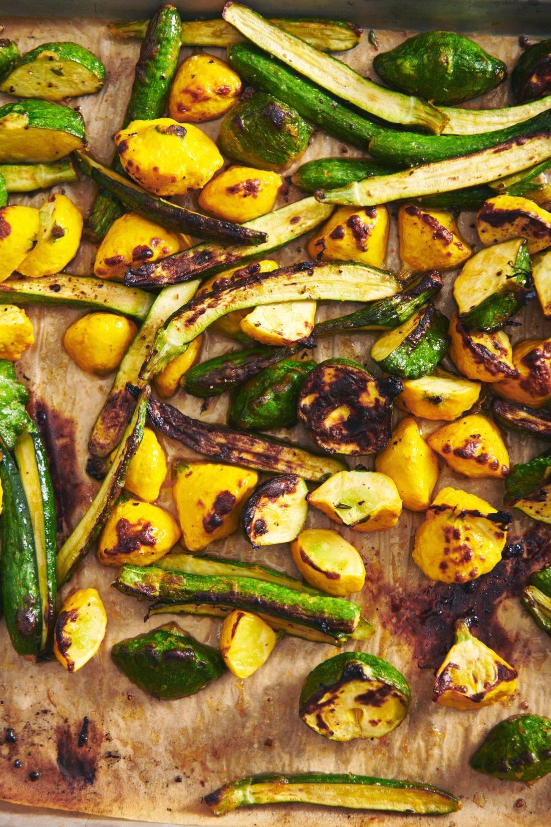 Green and yellow Roasted Baby Squash on a lined baking sheet.