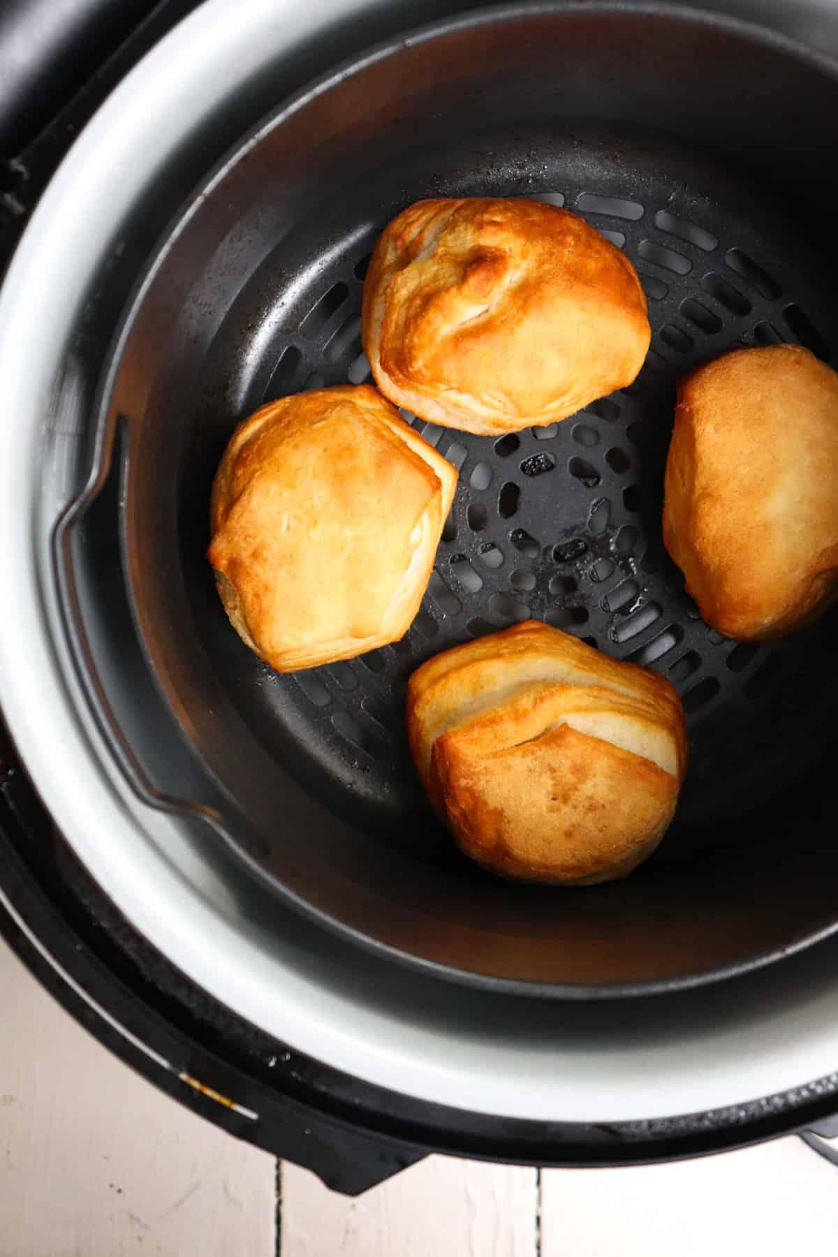 4 cooked biscuits in air fryer basket.