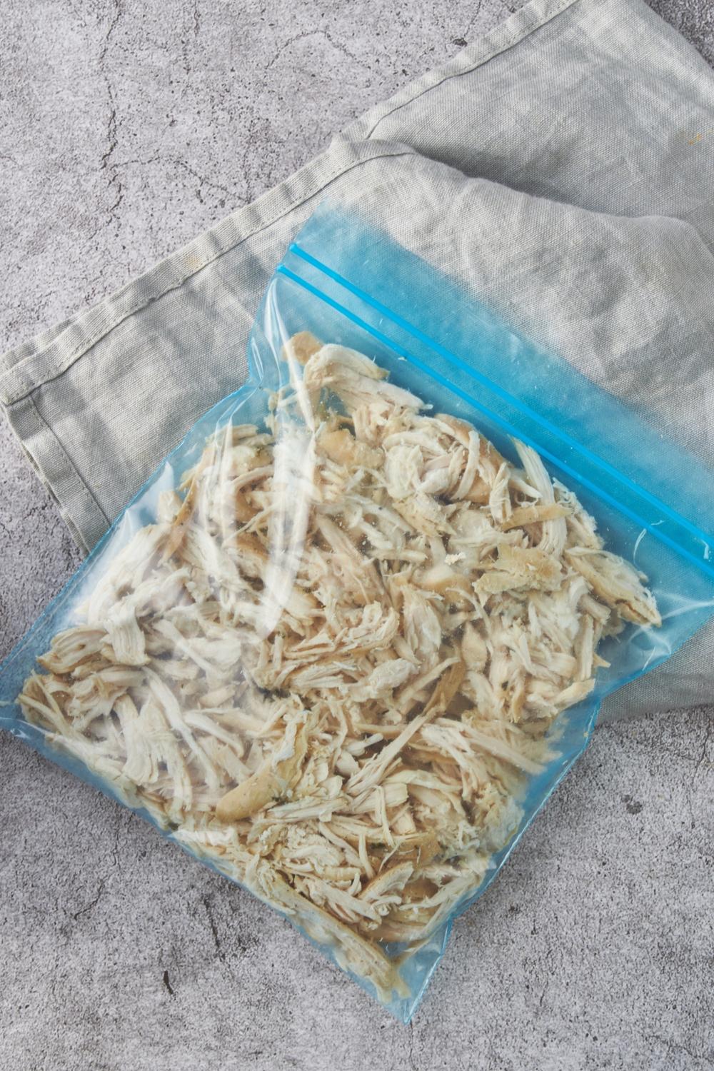A blue resealable plastic bag filled with shredded chicken.