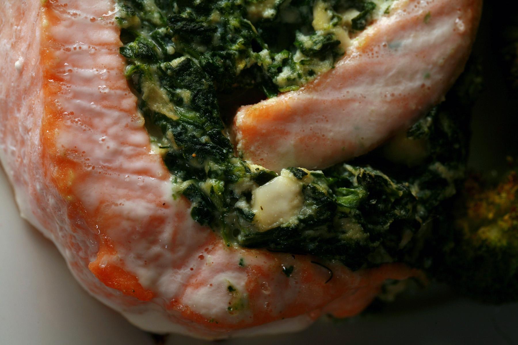 A serving of spinach and feta stuffed salmon, along with some roasted broccoli on a plate.