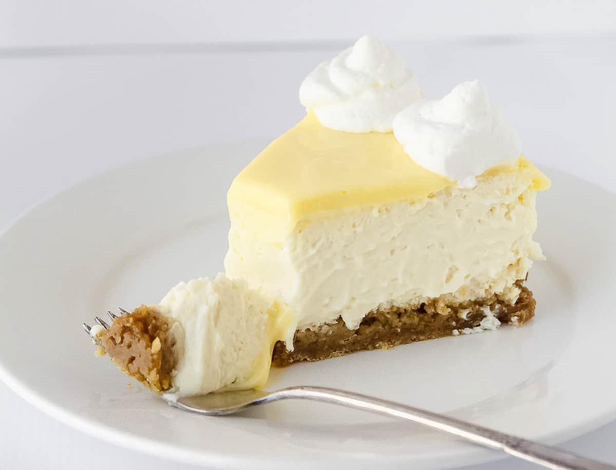 A slice of lemon cheesecake on a plate with a fork.
