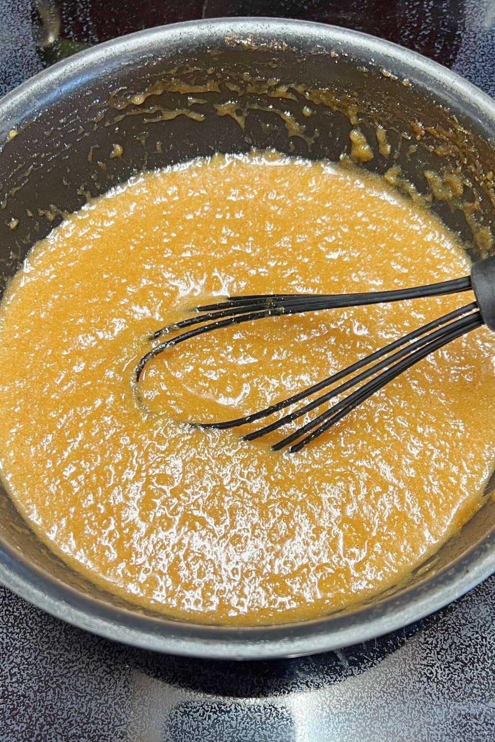 Ham glaze simmering in a saucepan on the stove.