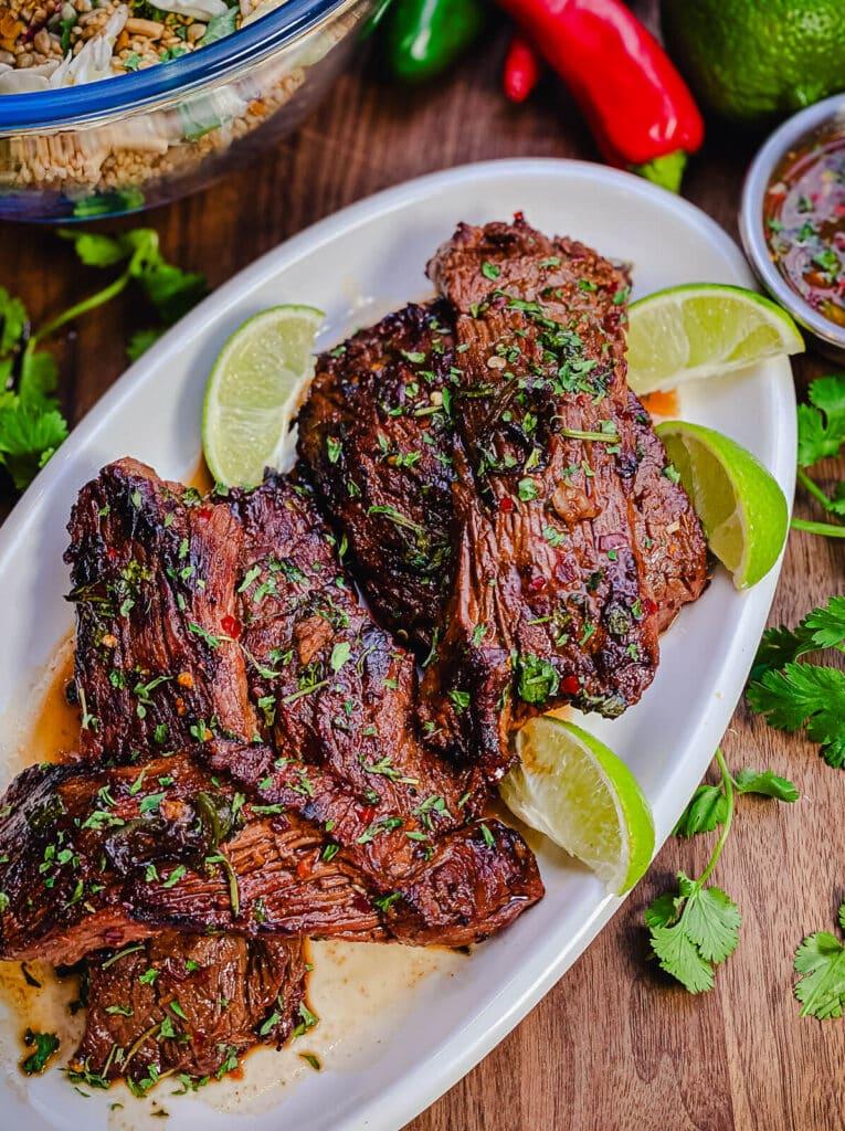 grilled steaks with limes on a white platter