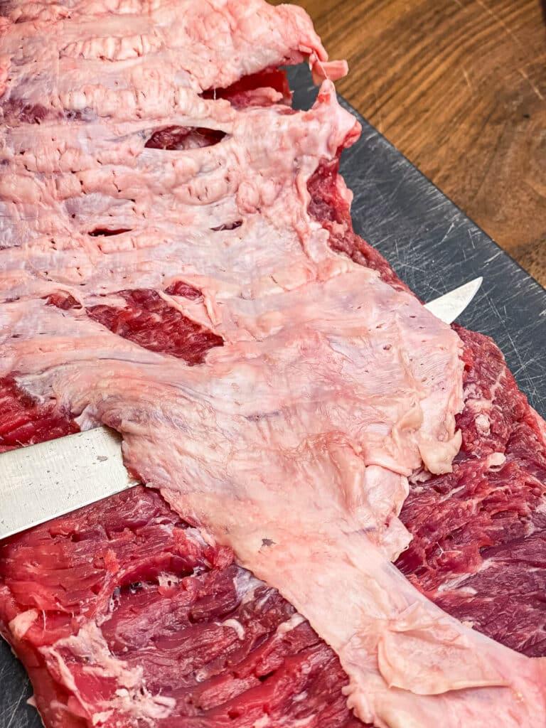 knife slicing off fat on flap meat