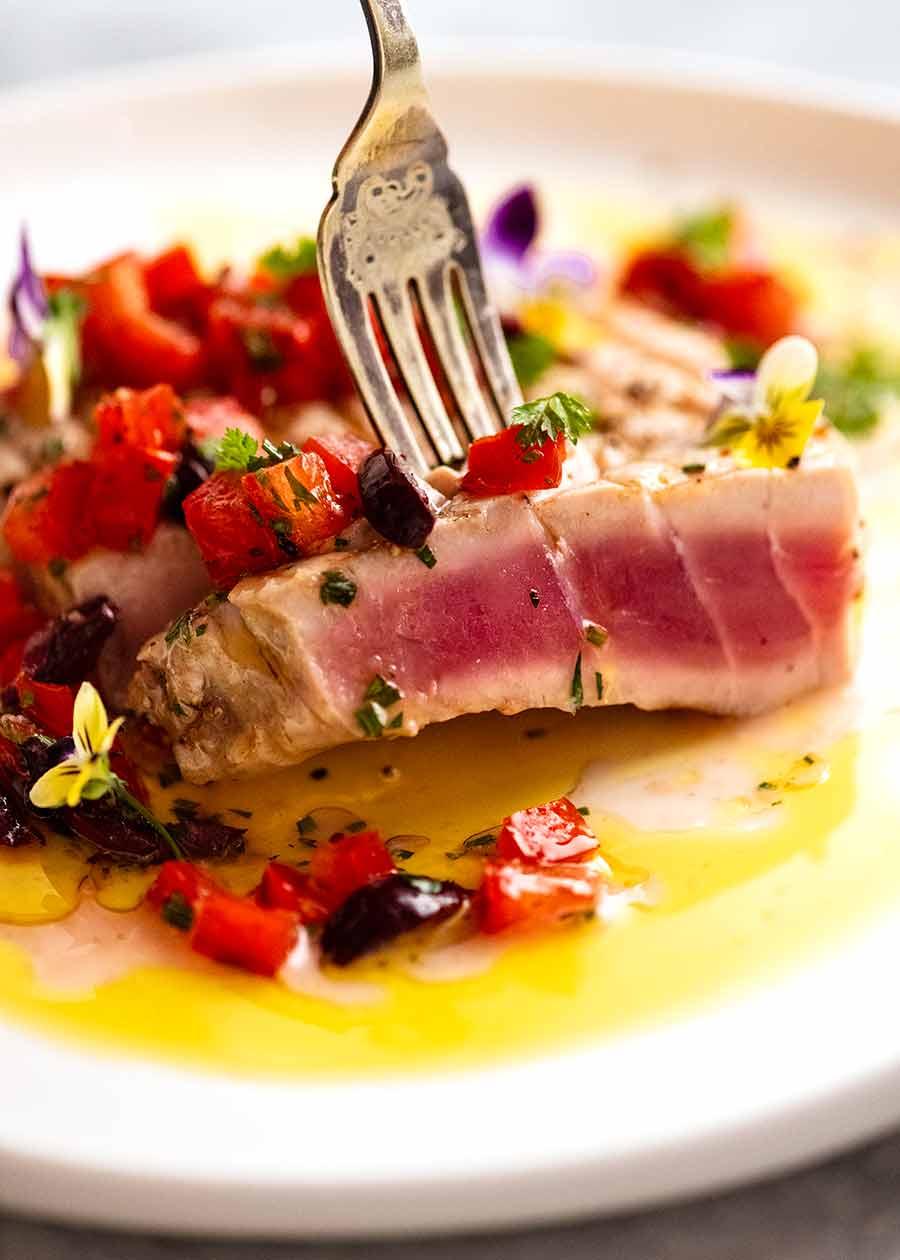 Close up of fork picking up a slice of tuna steak