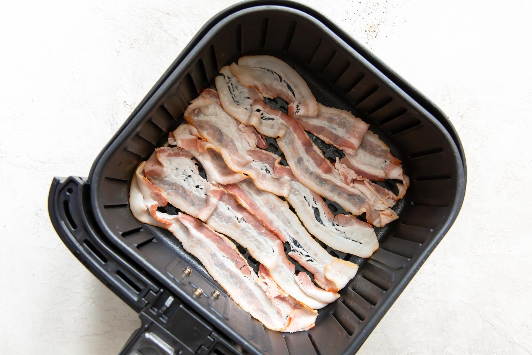 uncooked bacon slices in air fryer basket