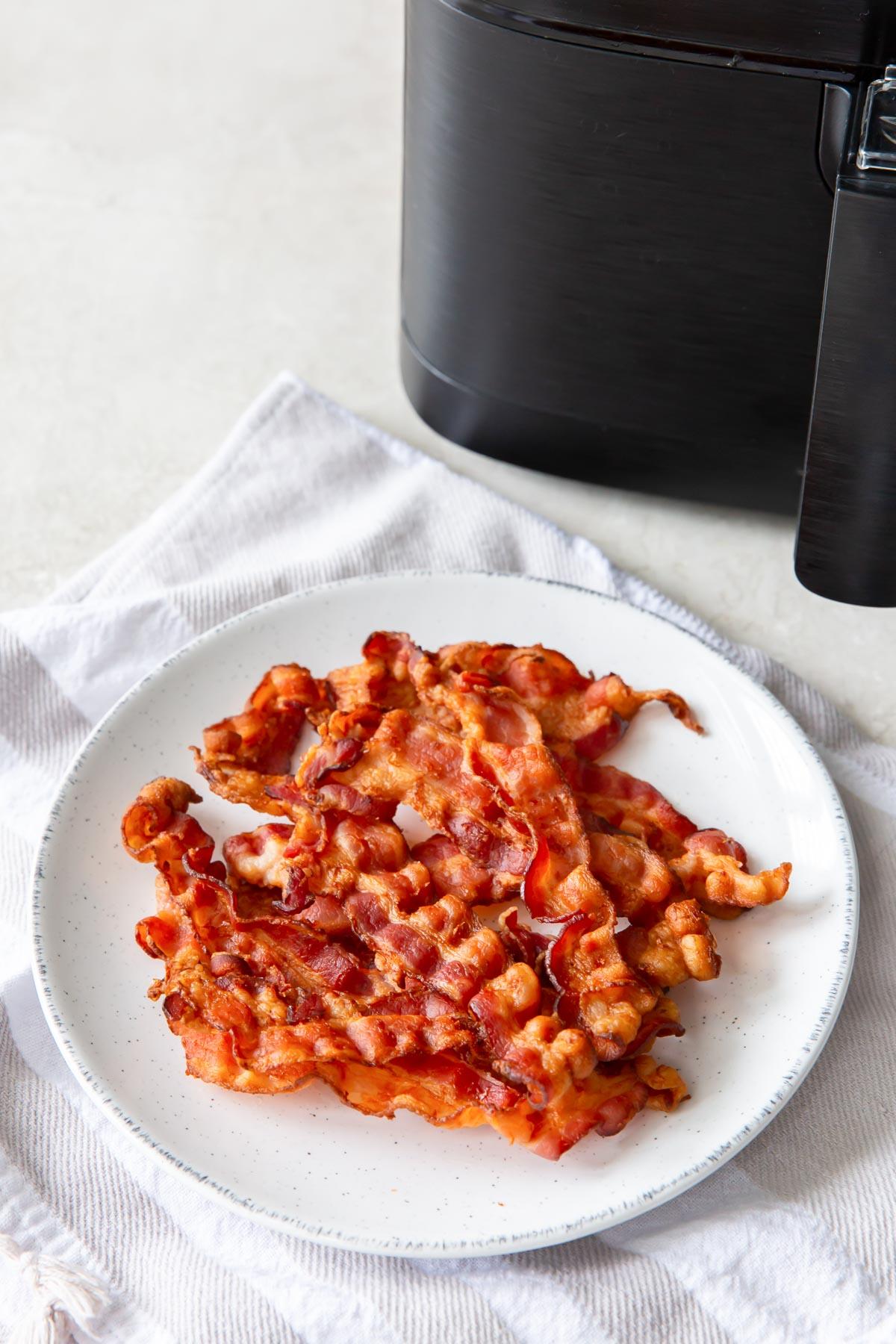 bacon on a plate in front of an air fryer
