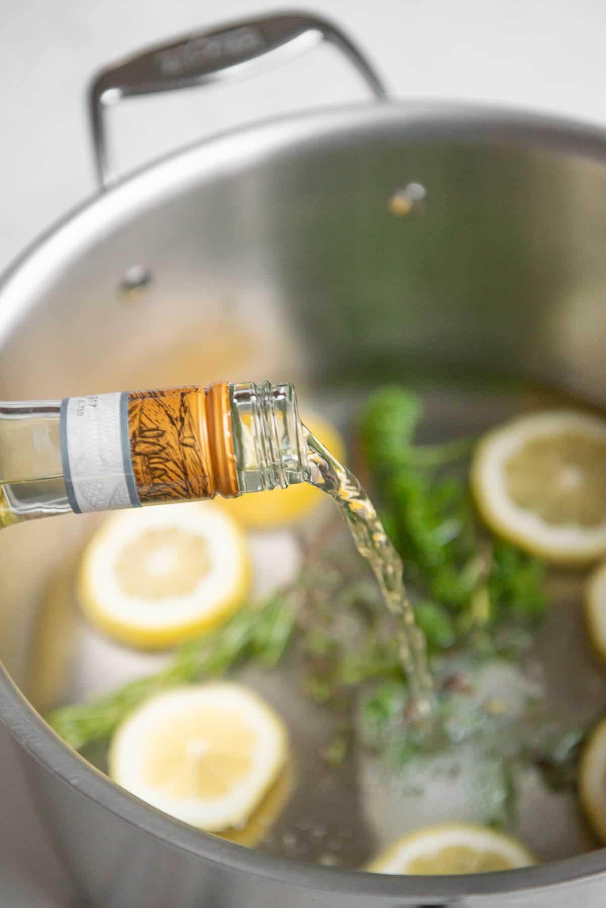 adding white wine to pot with lemon and herbs.