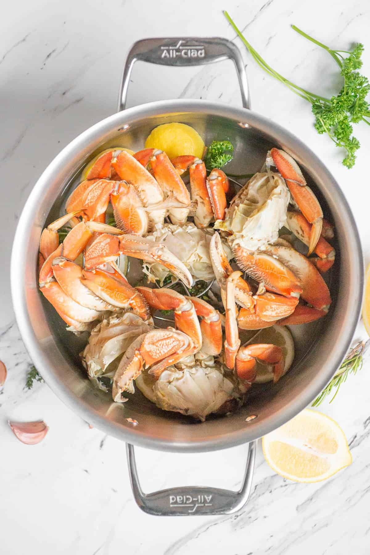 adding Dungeness crab legs to pot with aromatics to steam.