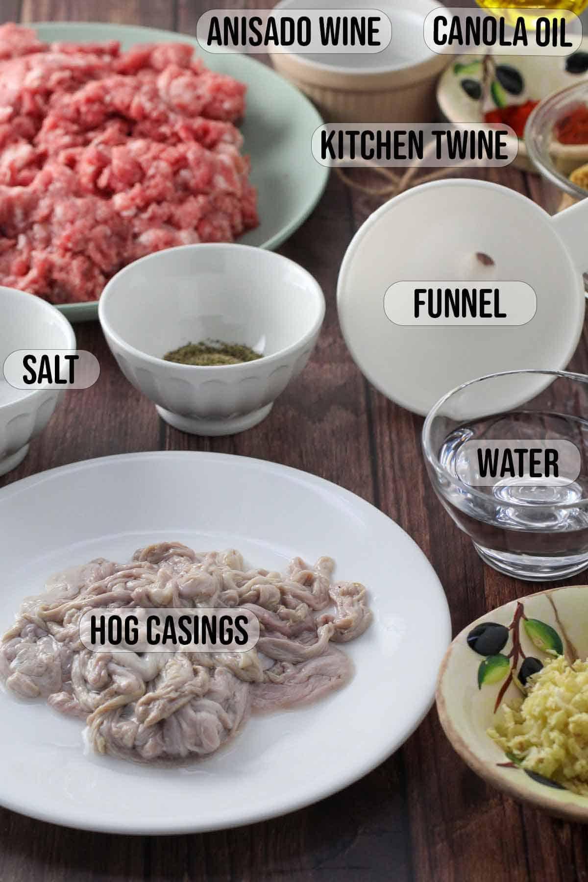 hog casings, ground pork, funnel, salt, anisado wine, garlic, water, canola oil in bowls