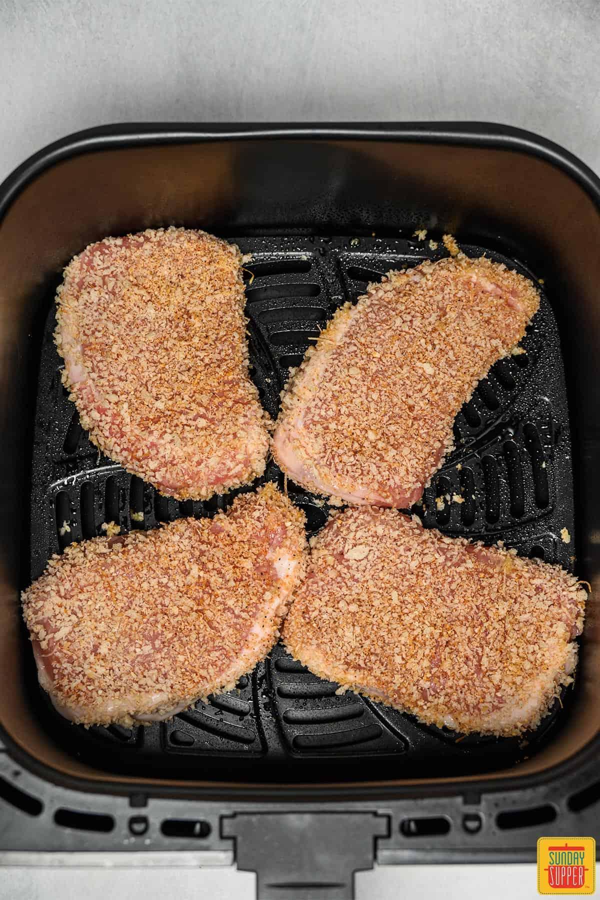 Breaded pork chops going inside the air fryer
