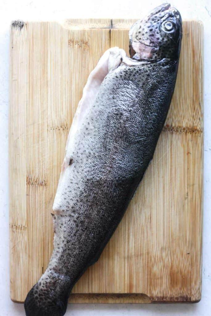 Raw Whole Rainbow Trout on the Wooden Cutting Board
