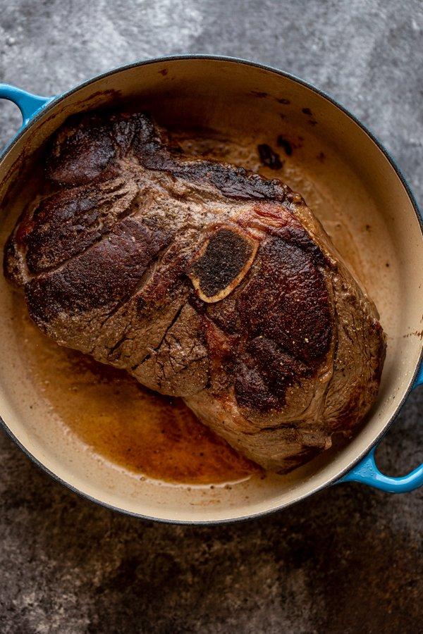searing a large piece of meat in a pan