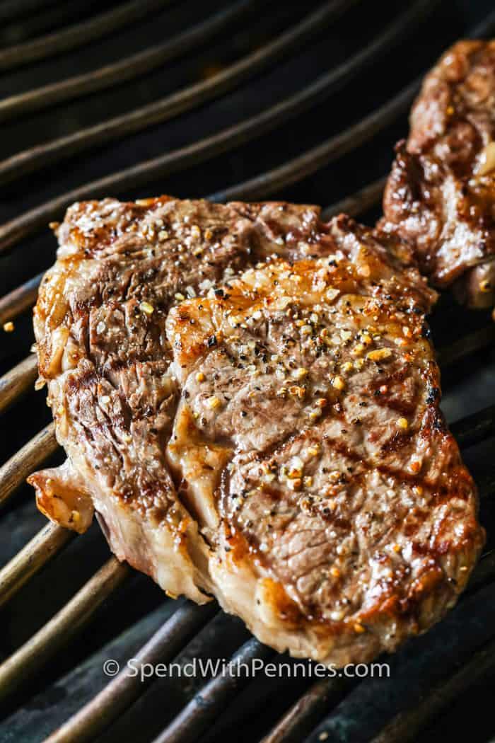 cooking steak on the grill to show How to Cook a Perfect Ribeye Steak