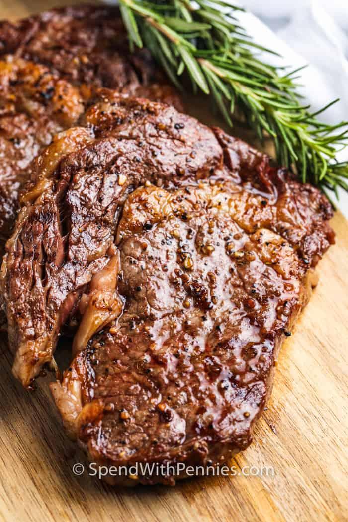 seasoned steak with garnish to show How to Cook a Perfect Ribeye Steak
