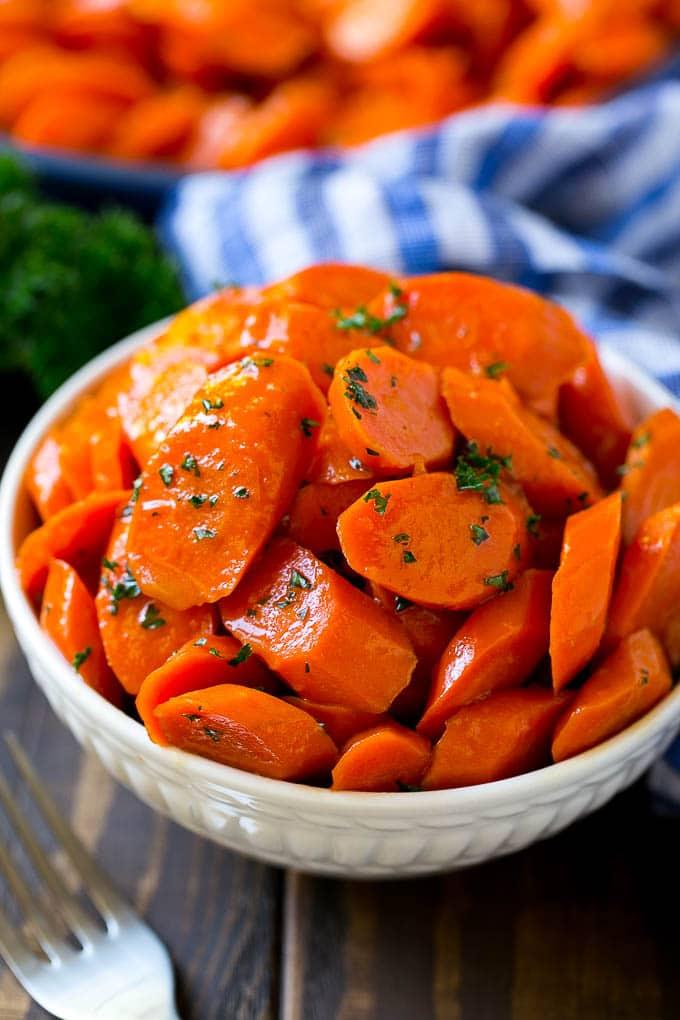 A bowl of glazed carrots topped with parsley.