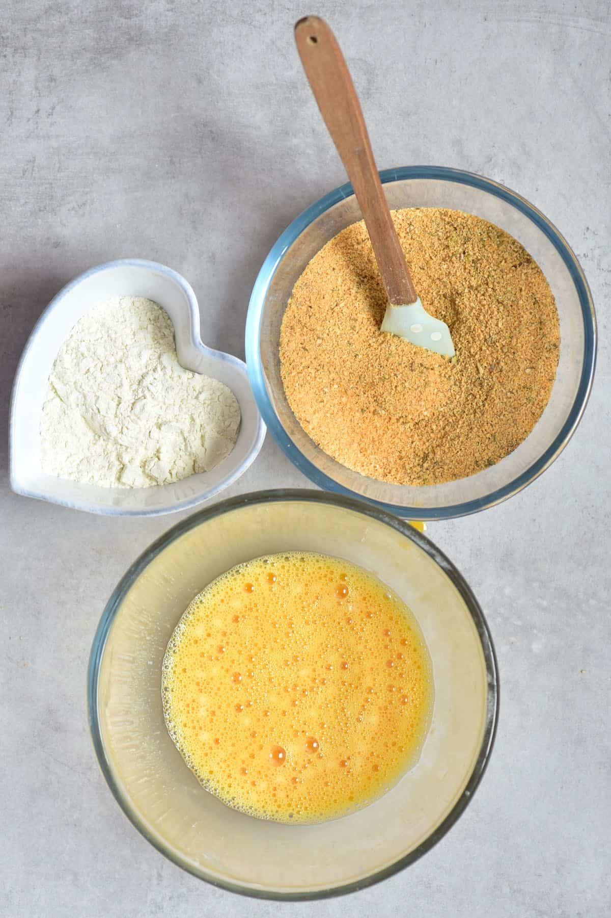 Three bowls with flour, with breadcrumbs, and with whisked eggs