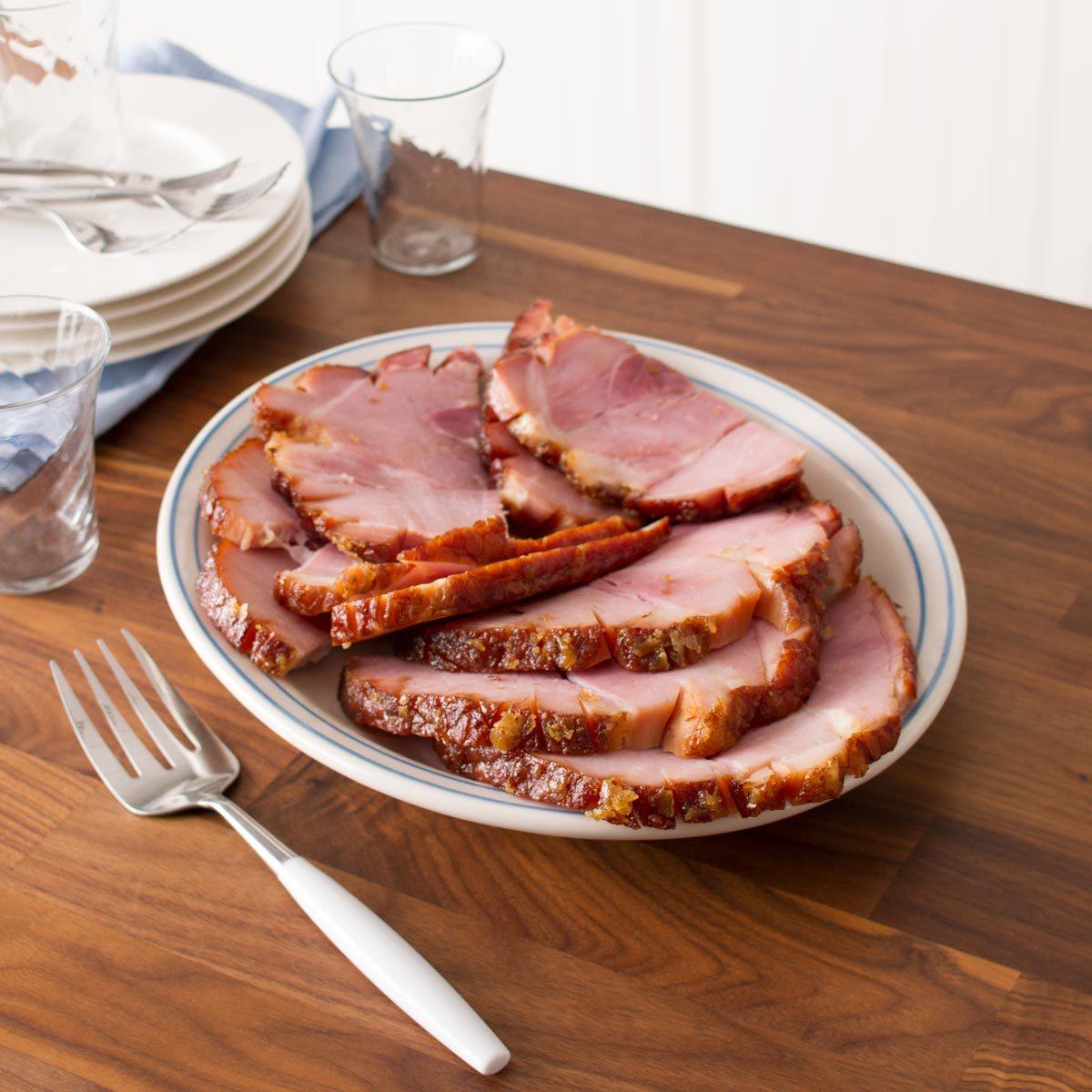 Plate of carved ham on a wood countertop