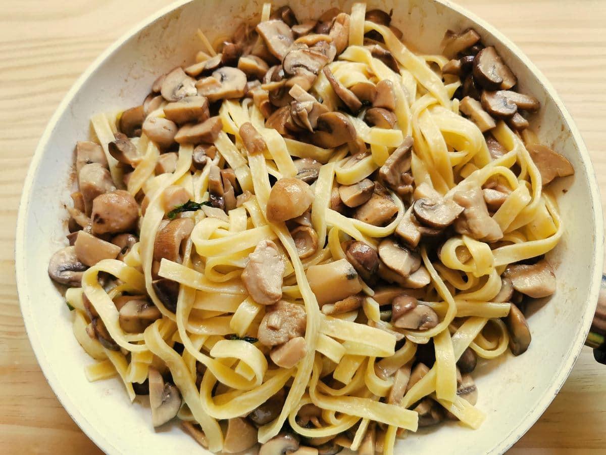 tagliatelle with porcini mushrooms mixed together in pan