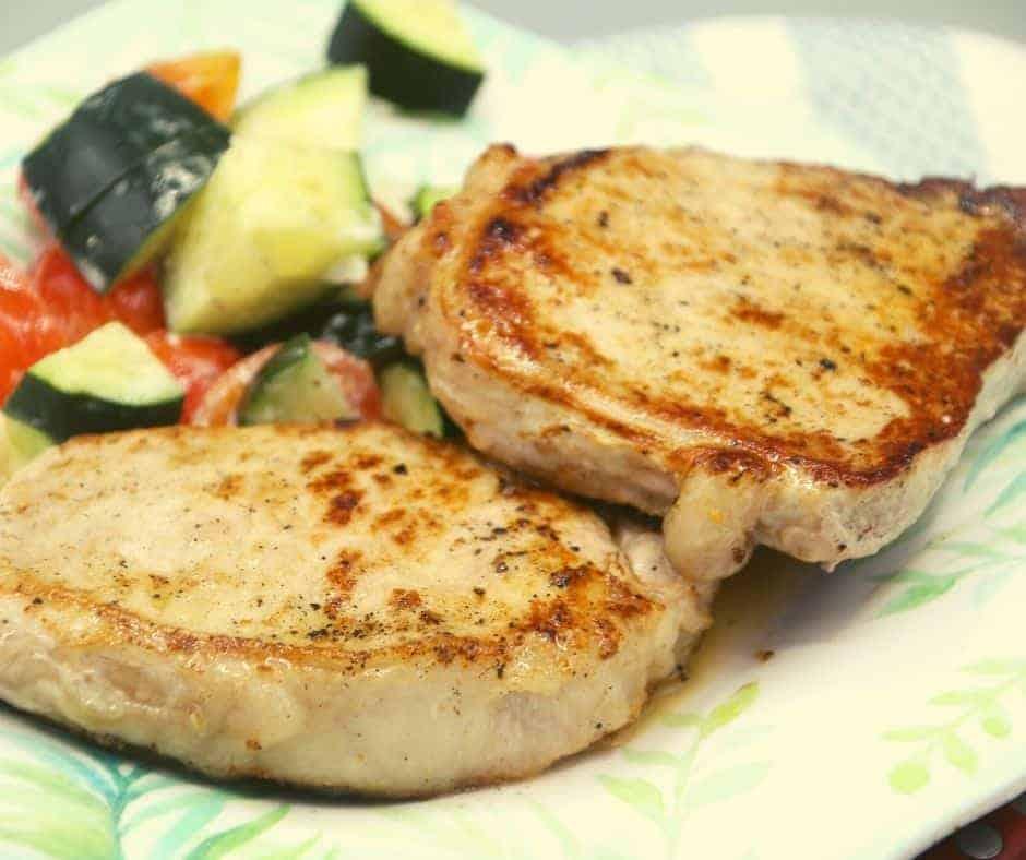 closeup: grilled pork chops on a plate with veggies on the side
