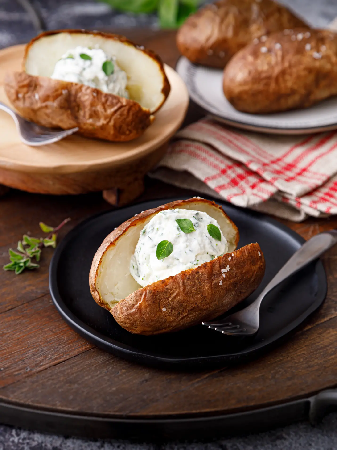Baked potato on a black plate cut open with a dollop of herbed ricotta. A delicious acid reflux-friendly dish