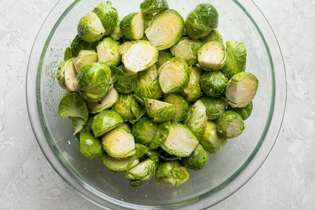 Brussels sprouts in a bowl with oil and seasonings