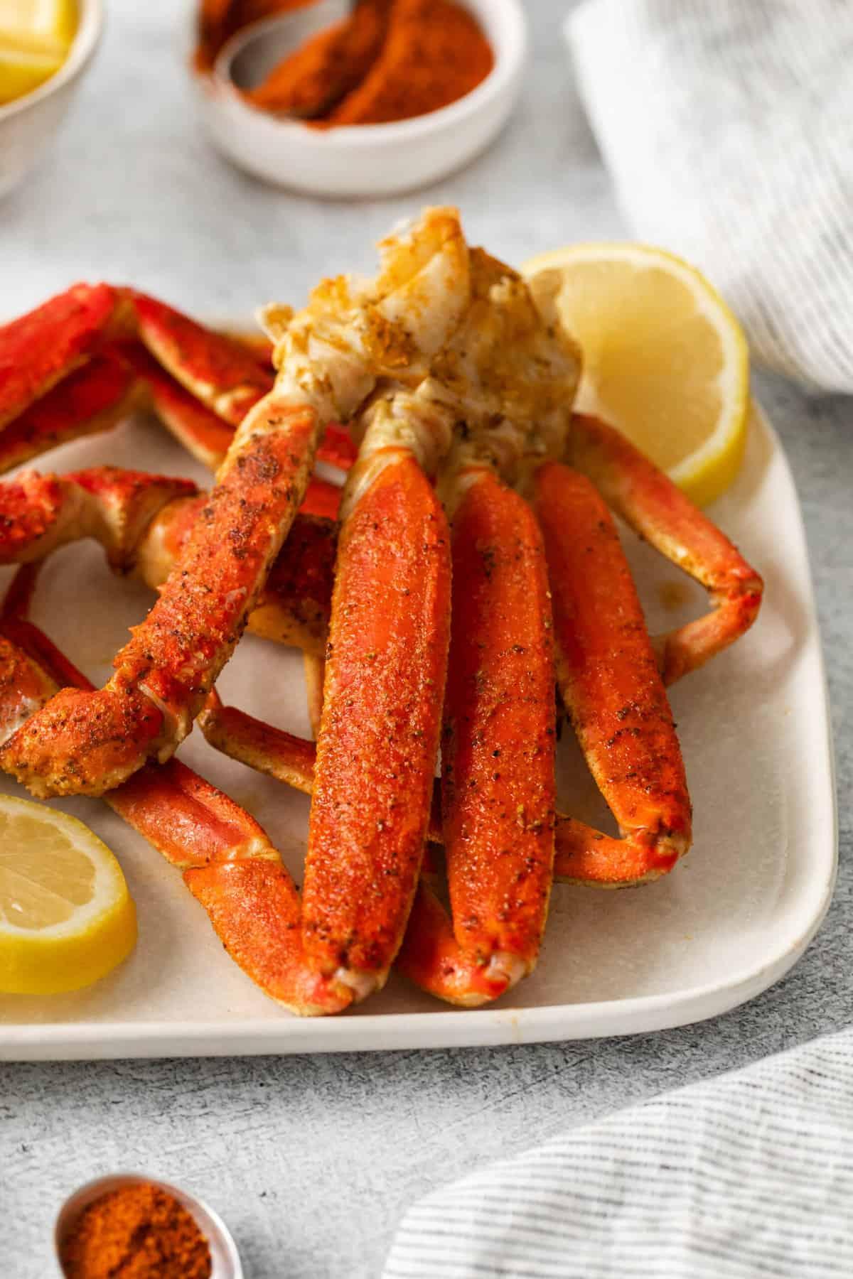 A plate of cooked snow crab with lemons.